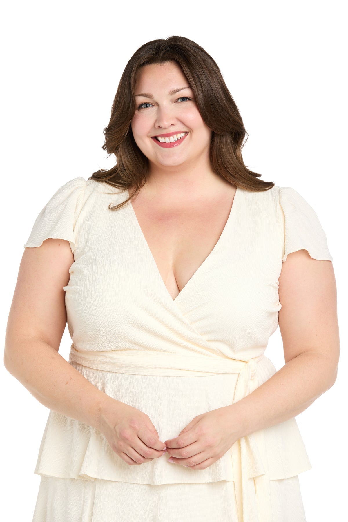 A woman with long brown hair wears the Plus-Size White Party Dress: R&M Richards 6677W, short-sleeved and perfect for parties, standing and smiling against a plain white background.